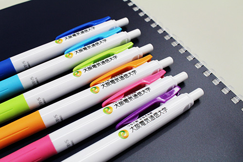 シンボルマークおよびタグラインをデザインした新しいボールペンを生協で販売しています 19年 新着情報 大阪電気通信大学